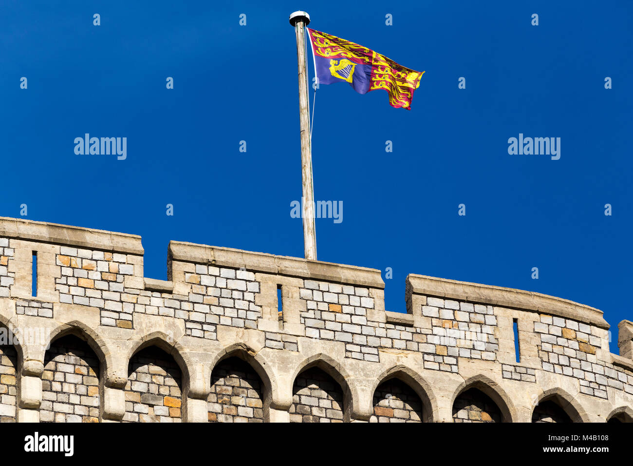 The Royal Standard flag flying on / from a flagpole / pole at Windsor Castle, UK. It is flown at royal residences only when the sovereign is present. Stock Photo