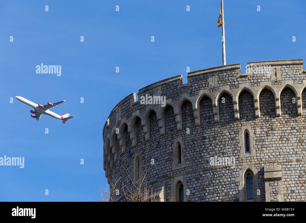 Aircraft / aeroplane / air plane / flight from Heathrow airport over the round tower of Windsor Castle, climbing after take off, & Royal Standard flag Stock Photo