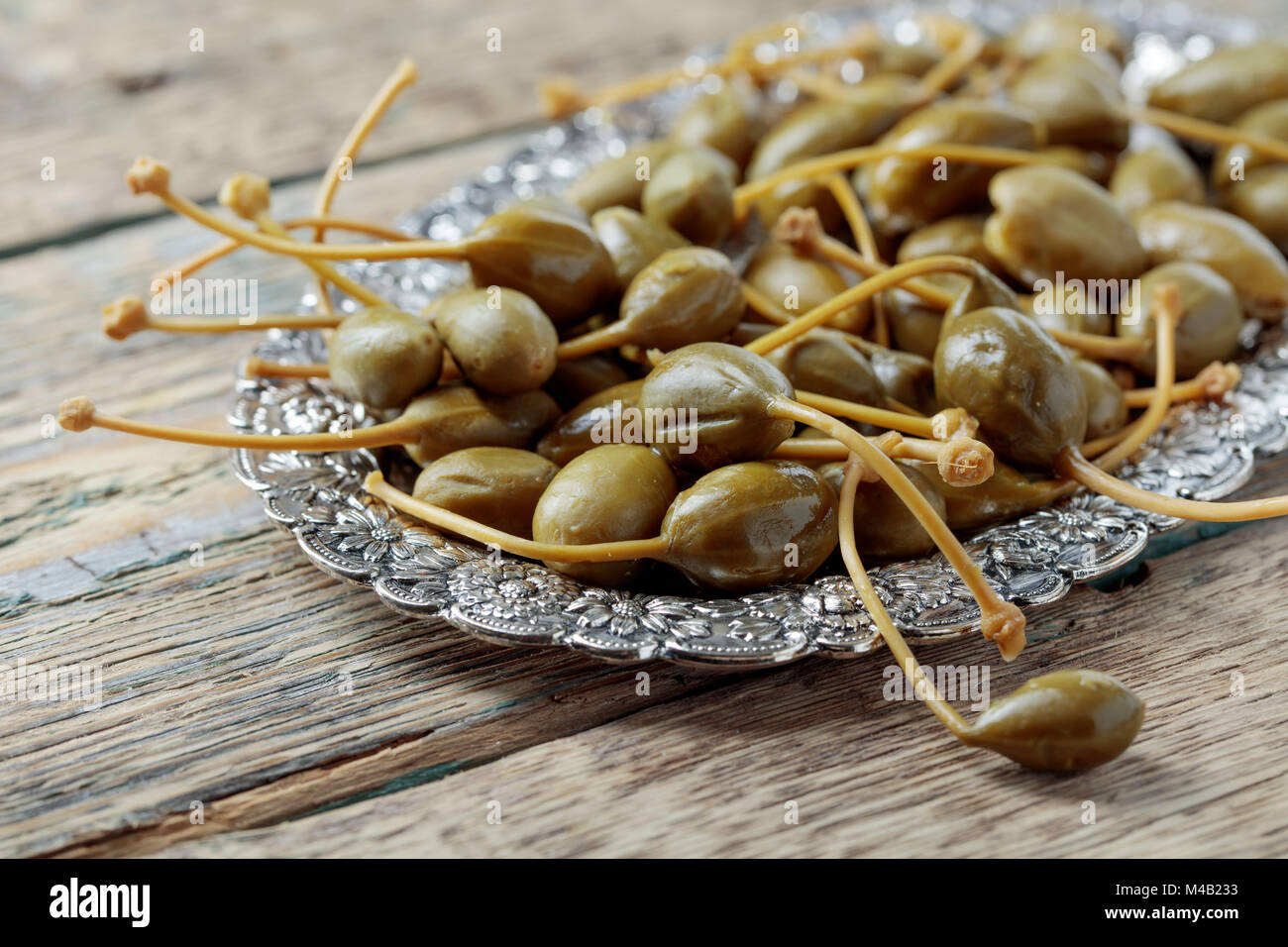 Pickled caper berries in metal dish . Edible fruits of Capparis