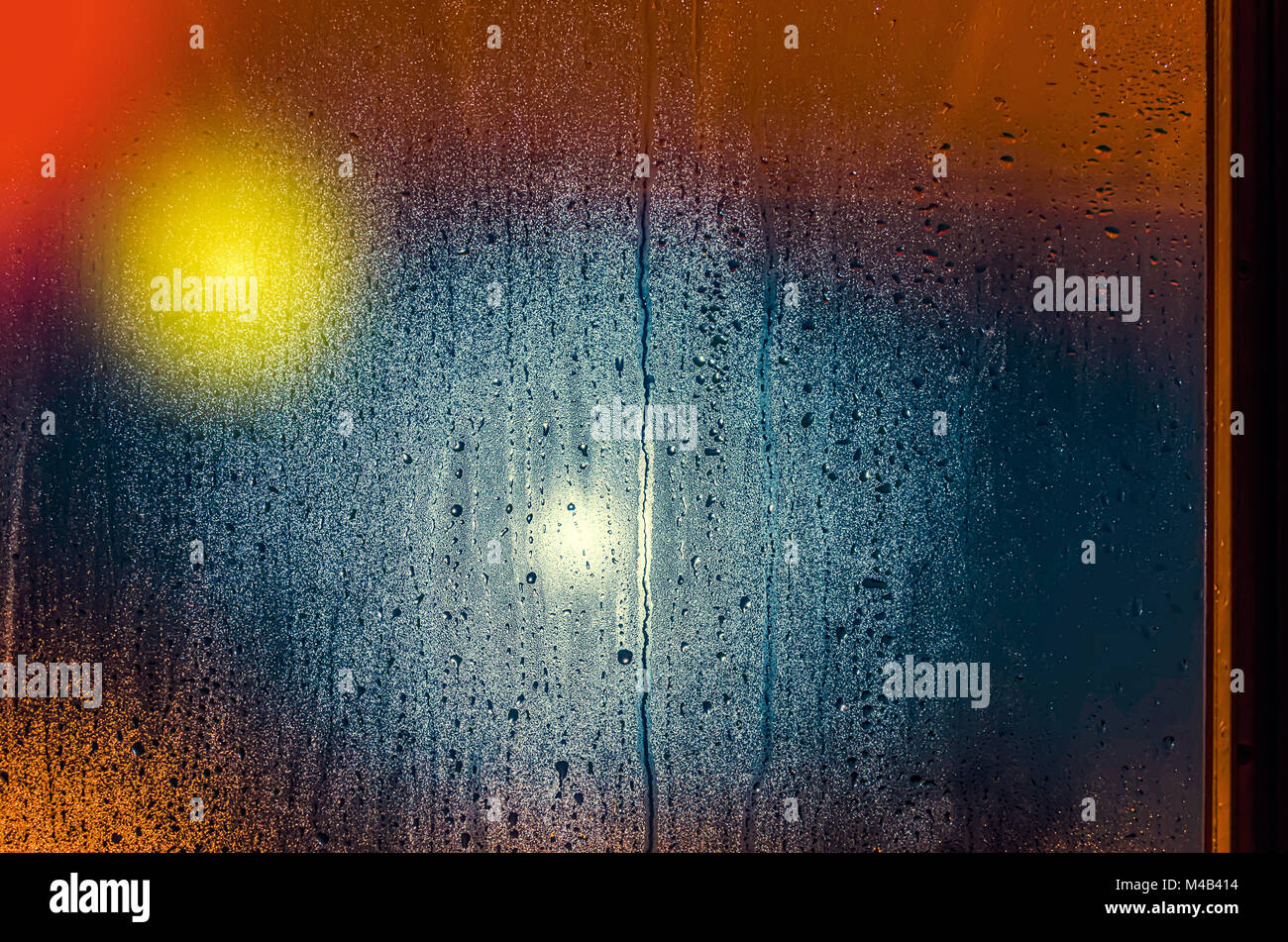 Drops and water spots on the glass on a rainy evening, multicolored spots and lights shining Stock Photo
