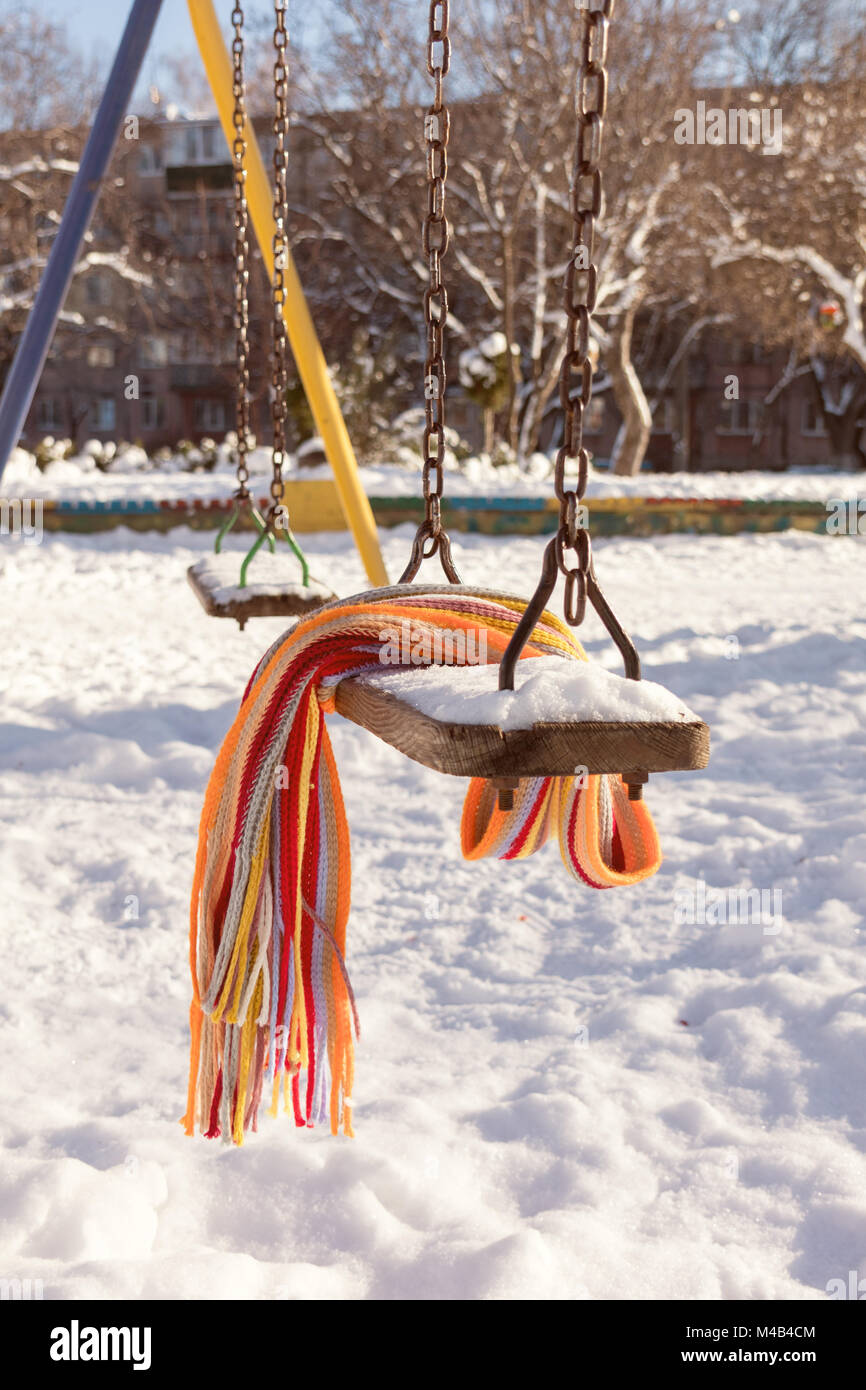 Empty swing with snow and checkered scarf Stock Photo