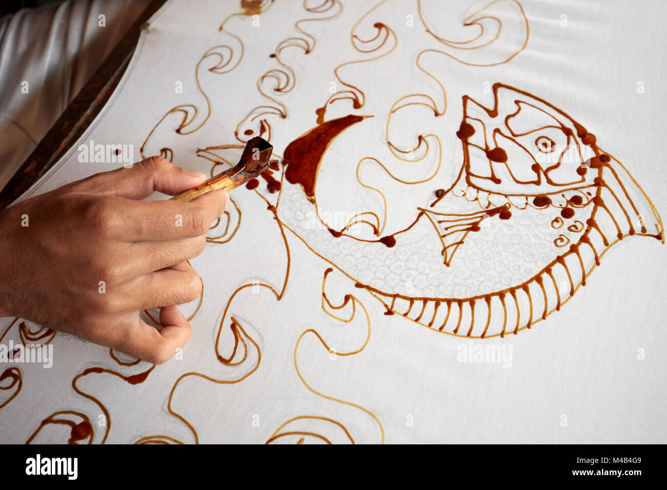 A batik maker applies melted wax on cloth with a canting (spouted tool). Yogyakarta, Java, Indonesia. Stock Photo