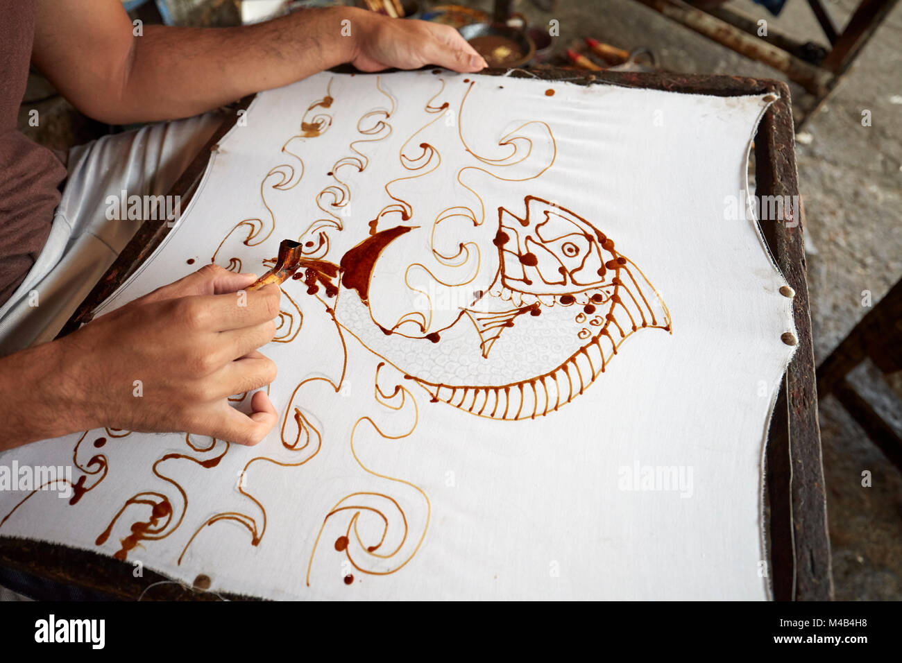 A batik maker applies melted wax on cloth with a canting (spouted tool). Yogyakarta, Java, Indonesia. Stock Photo