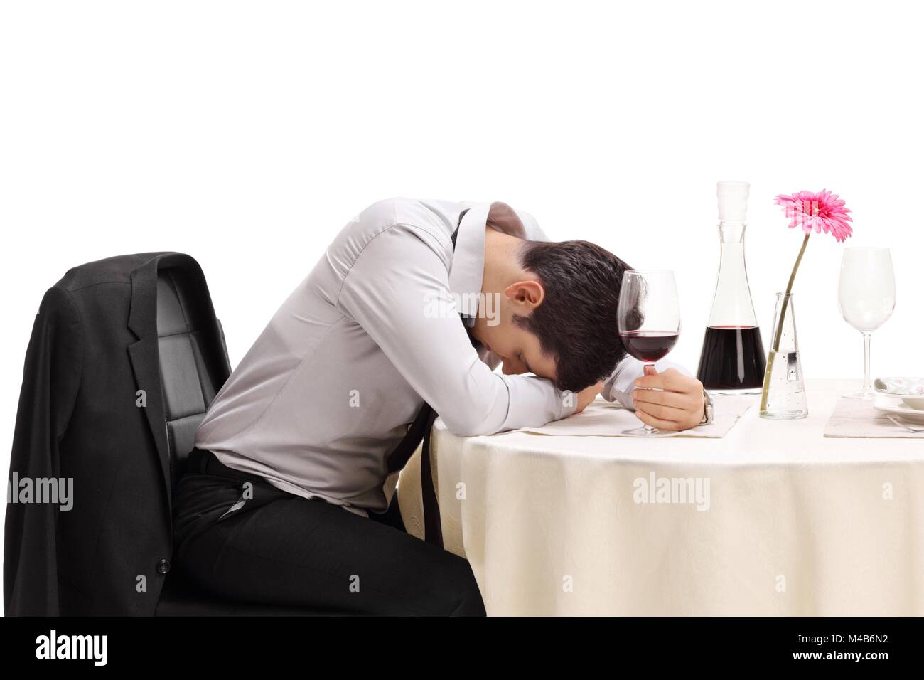 Drunk man sitting at a restaurant table with his head down isolated on white background Stock Photo