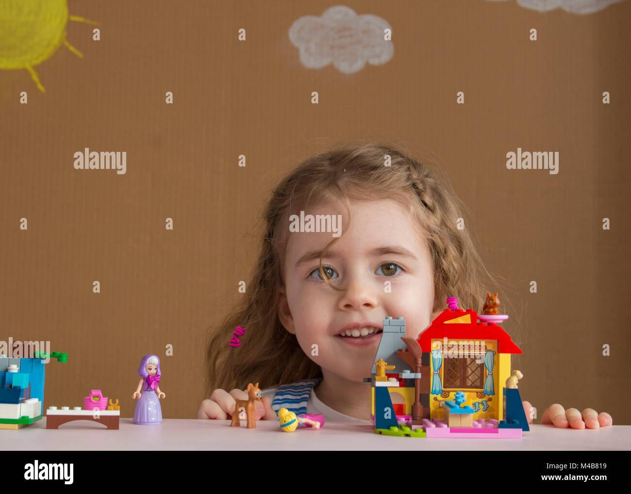 Cute funny preschooler little girl playing with construction toy blocks building a tower in