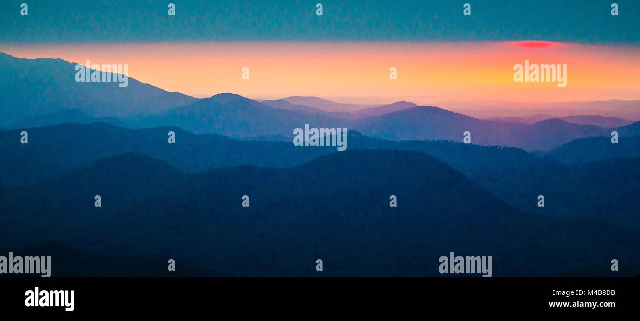 sunrise sun peeks through the clouds over mountain range Stock Photo ...