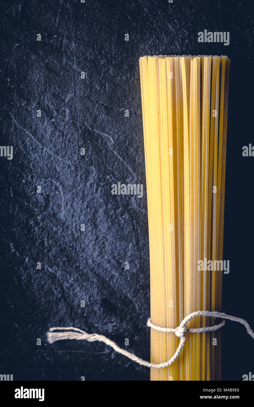 Raw spaghetti on the black stone background  vertical Stock Photo