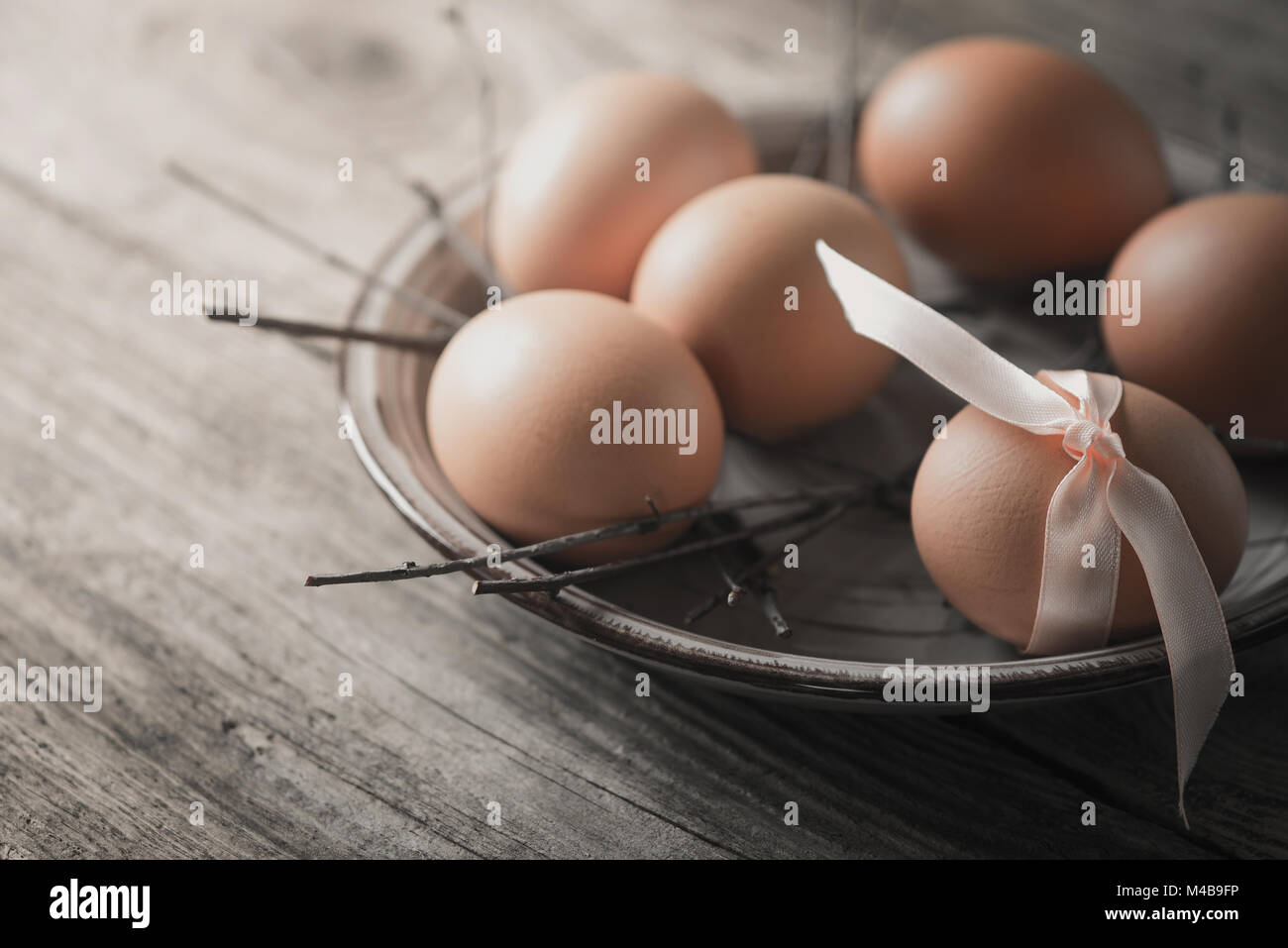 Eggs with  ribbon and branches on the wooden table Stock Photo