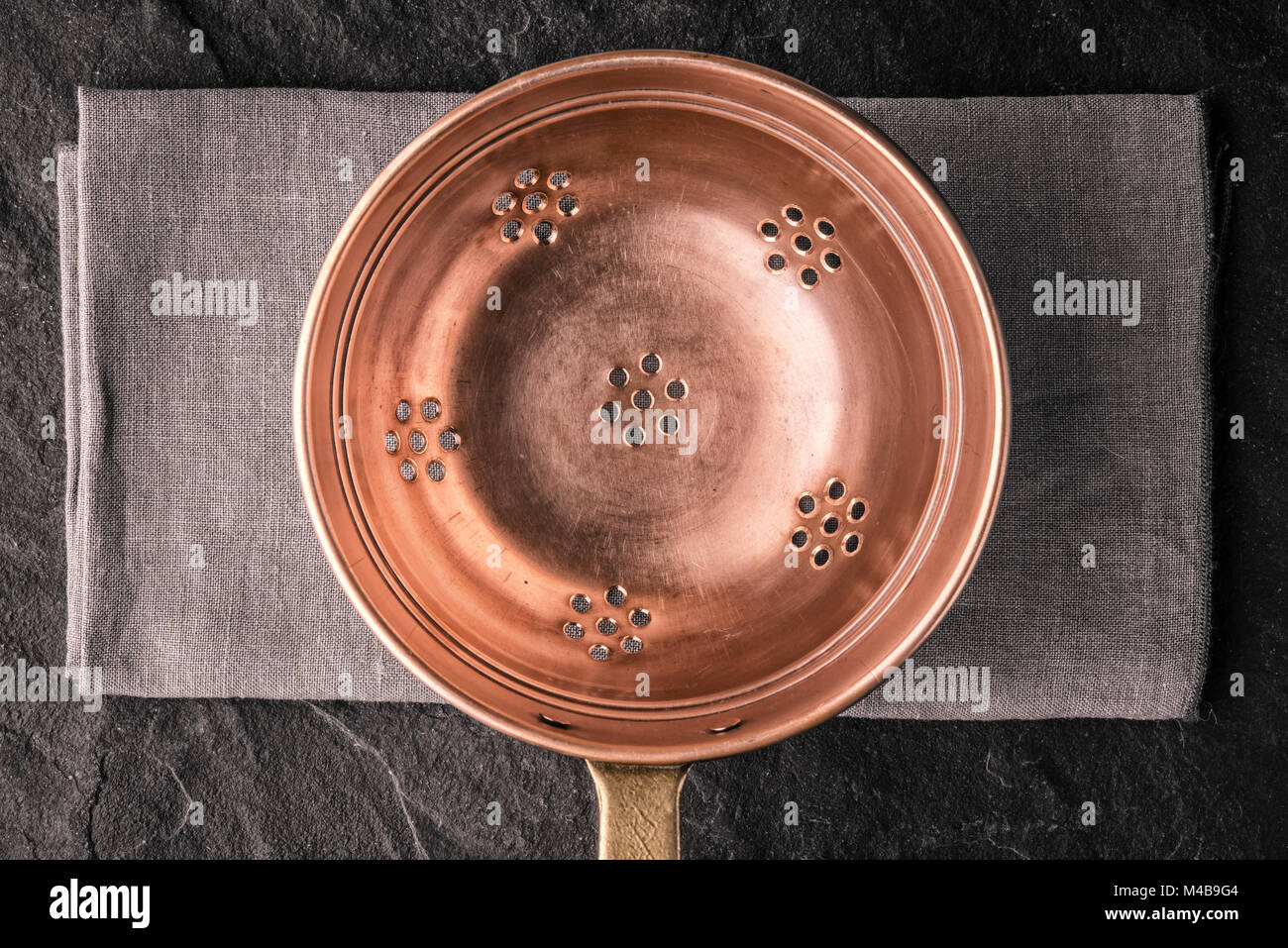 Copper colander on the dark stone table top view Stock Photo