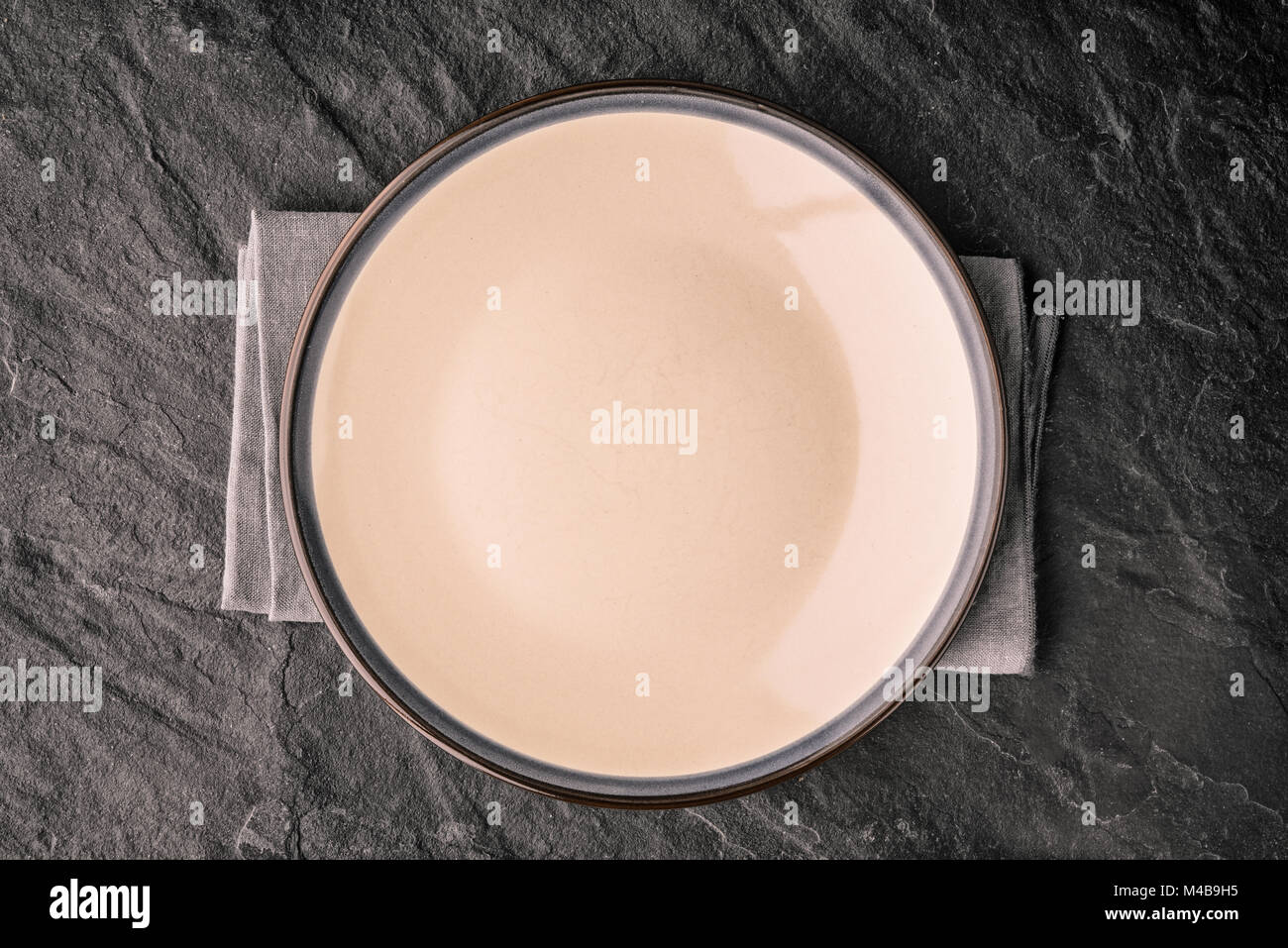 Ceramic plate on the dark stone table top view Stock Photo