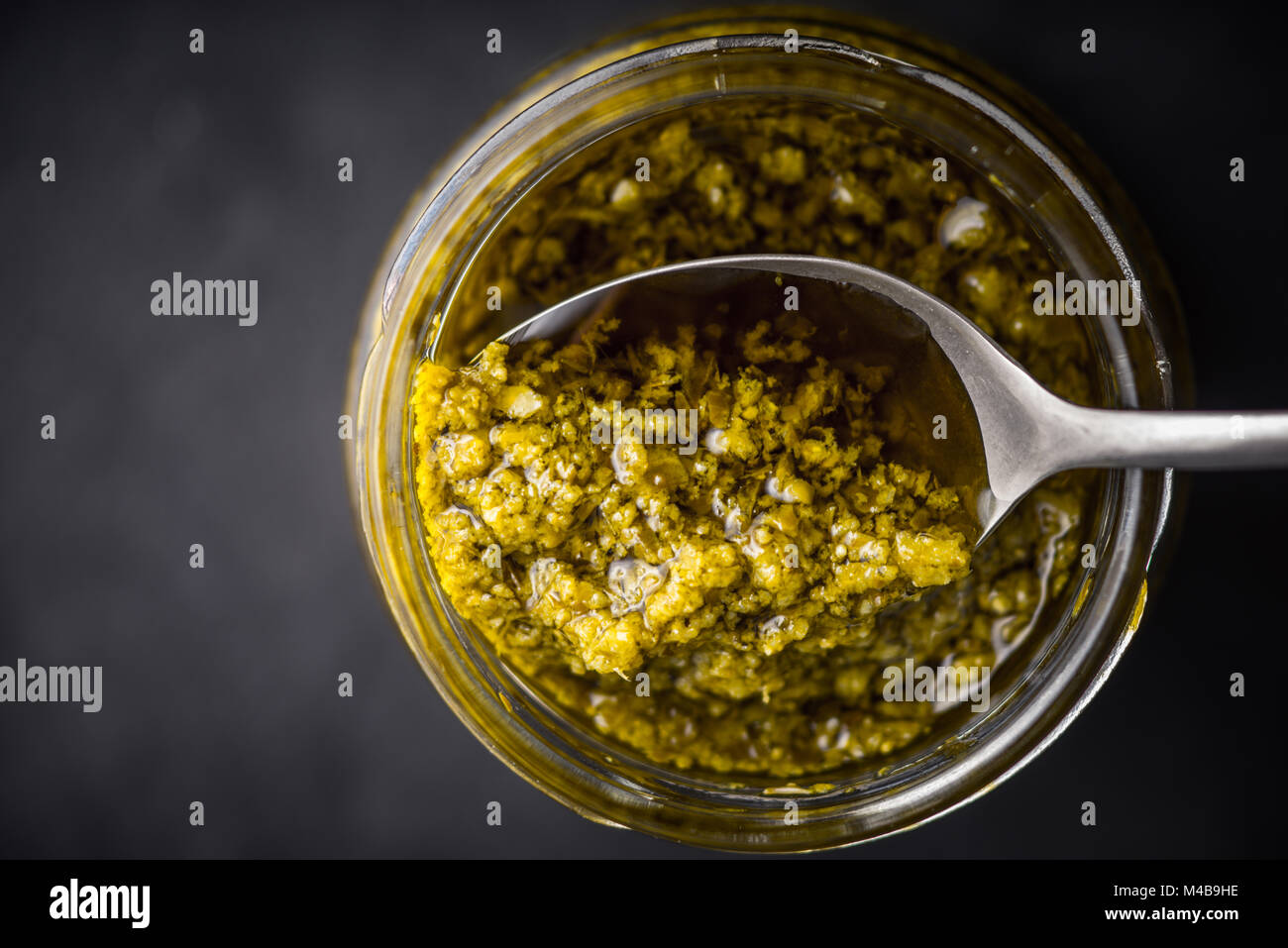 Pesto sauce in the glass jar with spoon top view Stock Photo