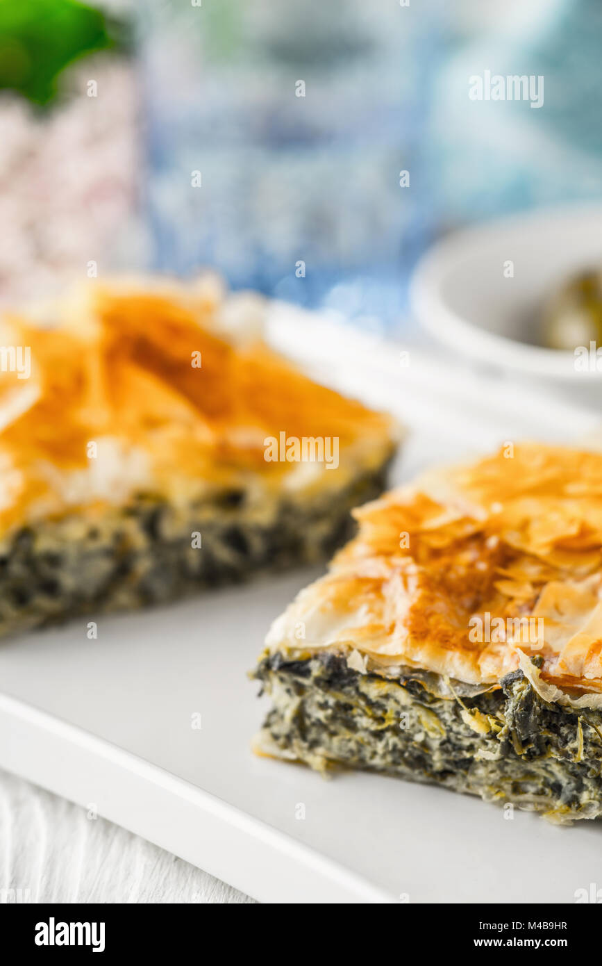 Greek pie spanakopita on the white plate with blurred accessorizes Stock Photo