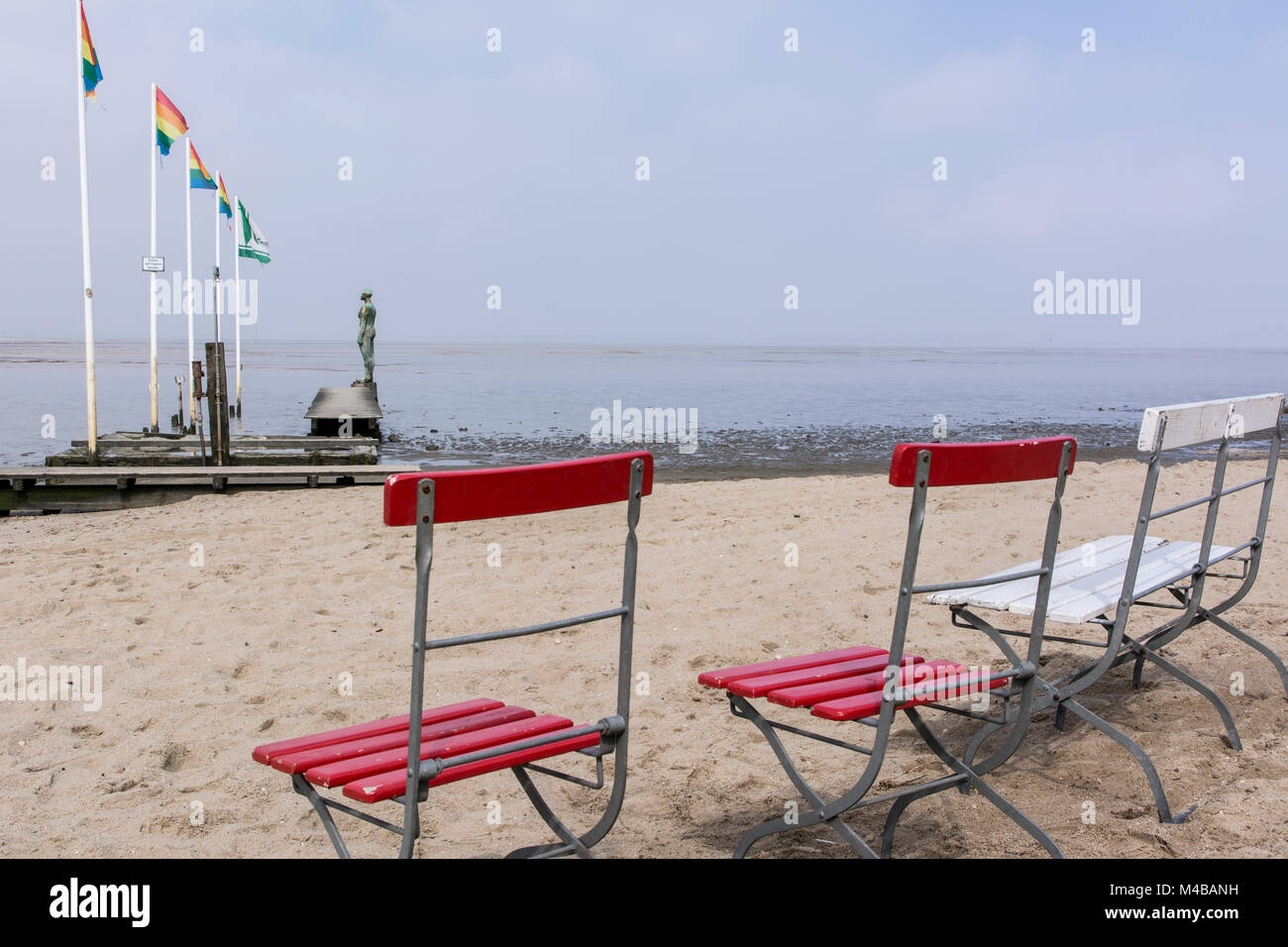 Stühle am Strand von Dangast mit Blick auf das Wattenmeer und ein Kunstwerk Stock Photo