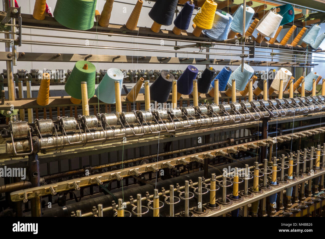 Colourful bobbins with yarns on twisting frame in cotton mill / spinning-mill Stock Photo