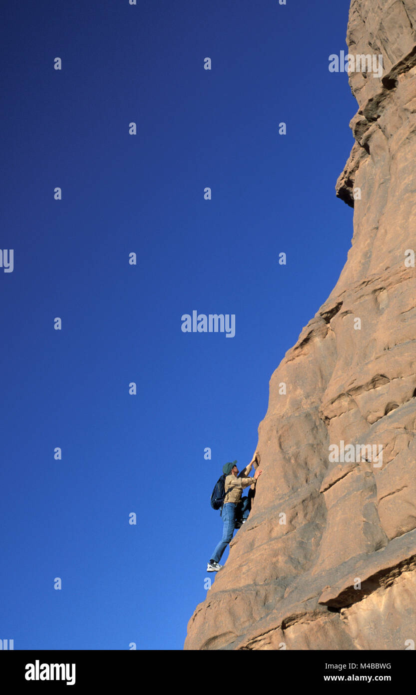 Algeria, Djanet. Sahara desert. National Park Tassili n'Ajjer.  Tourist. Woman climbing rock. UNESCO World Heritage site. *** Local Caption *** Algeri Stock Photo