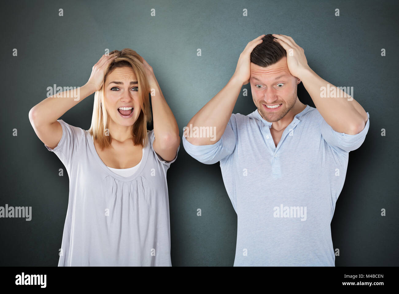 Portrait Of A Young Frustrated Couple Against Grey Background Stock Photo