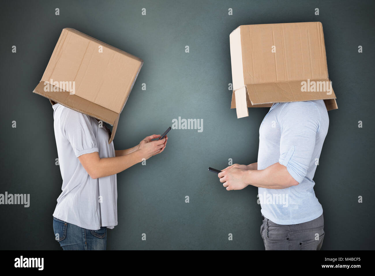 Couple Covering Their Heads With Cardboard box Using Cellphone Stock Photo