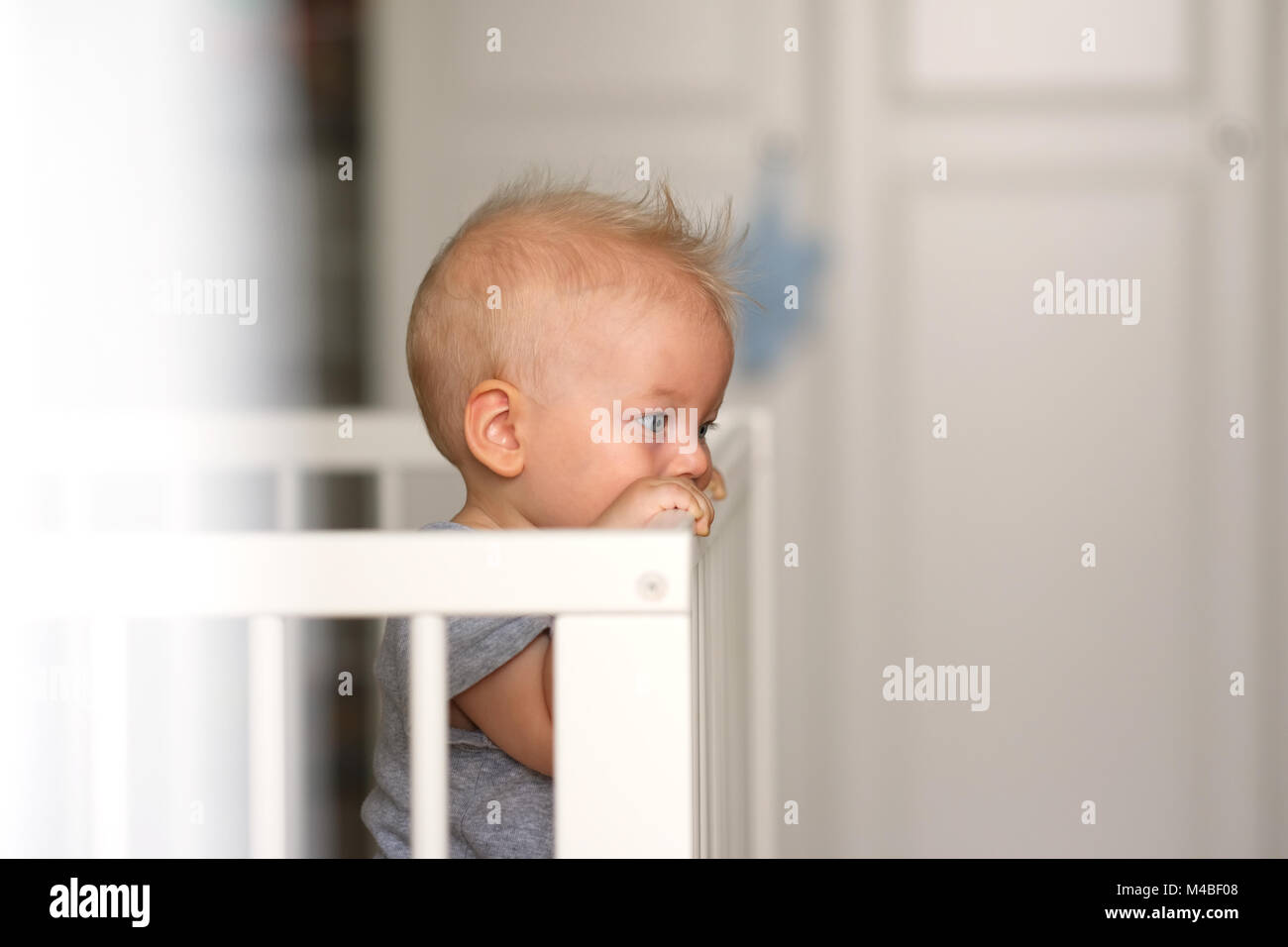 Baby boy standing in crib Stock Photo Alamy
