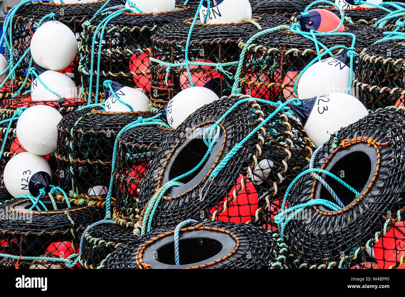 Lobster pots and traps stacked on a quay with floats and ropes ...