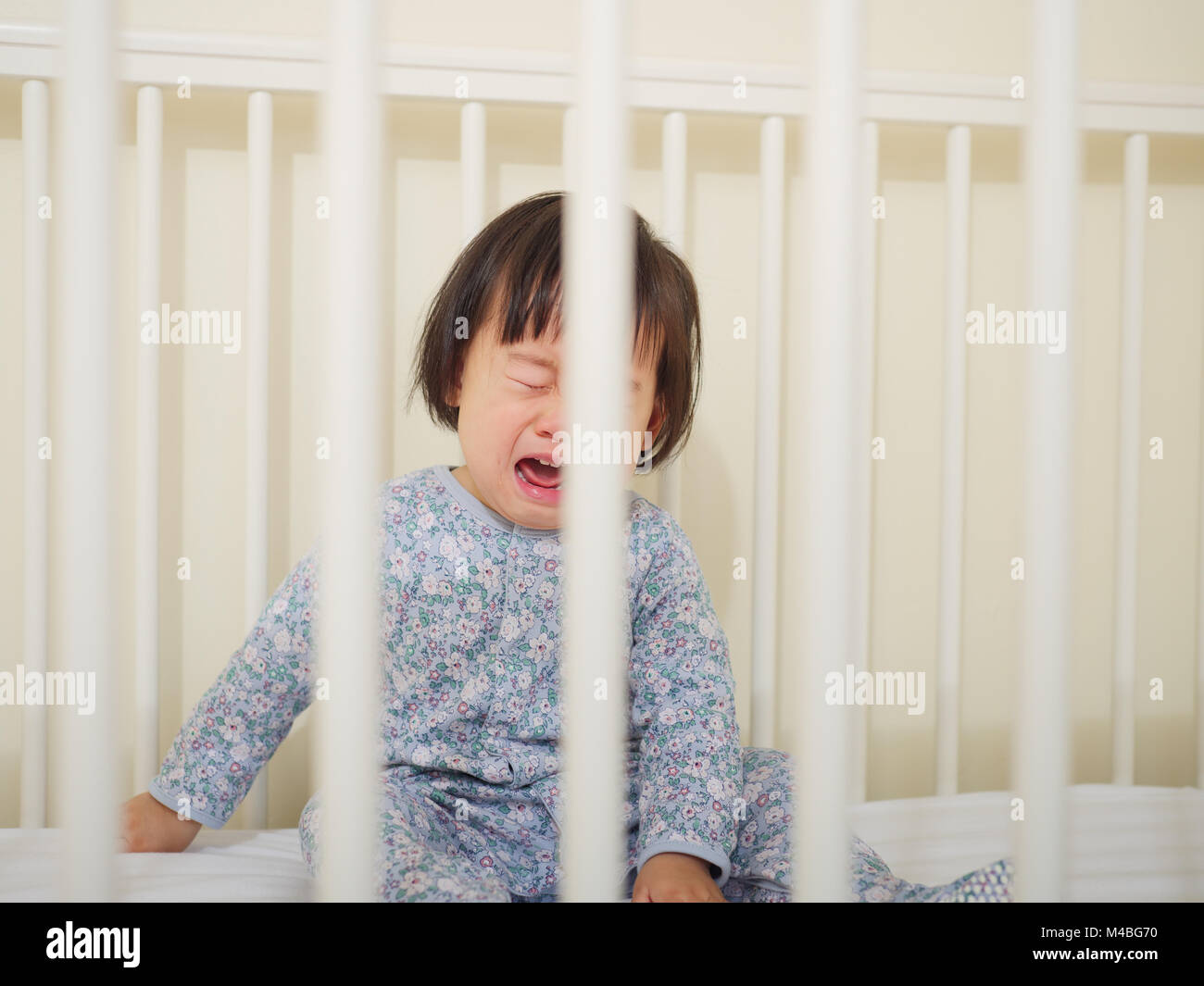 Crying Baby girl in cot bed Stock Photo Alamy