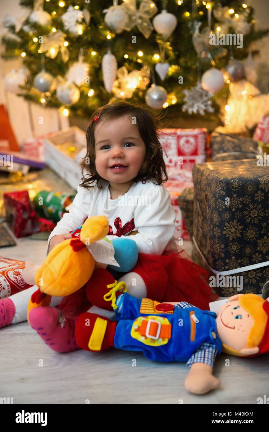 Baby while unpacking gifts at the Christmas tree Stock Photo