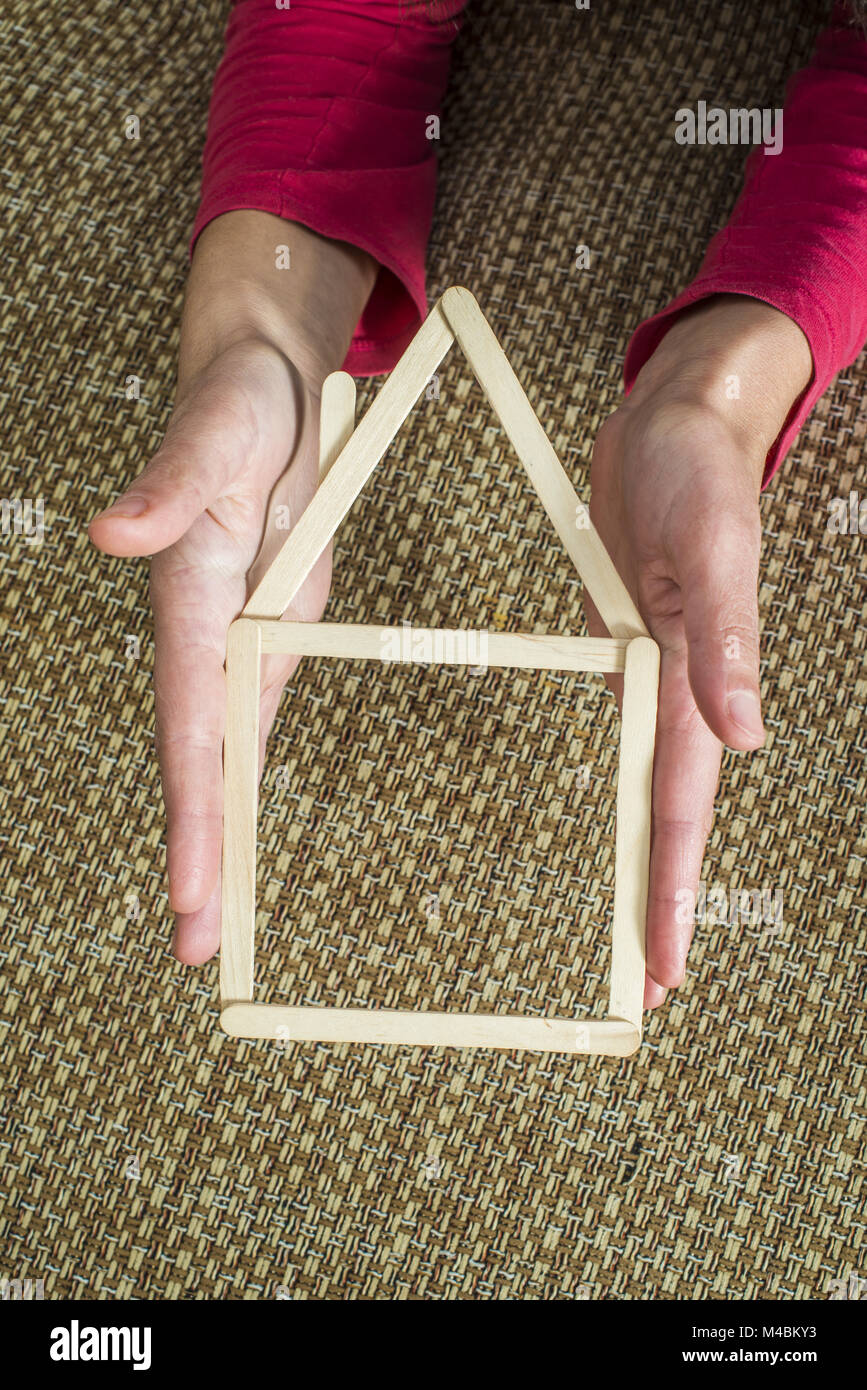 Hands holding model house made of wooden sticks Stock Photo - Alamy