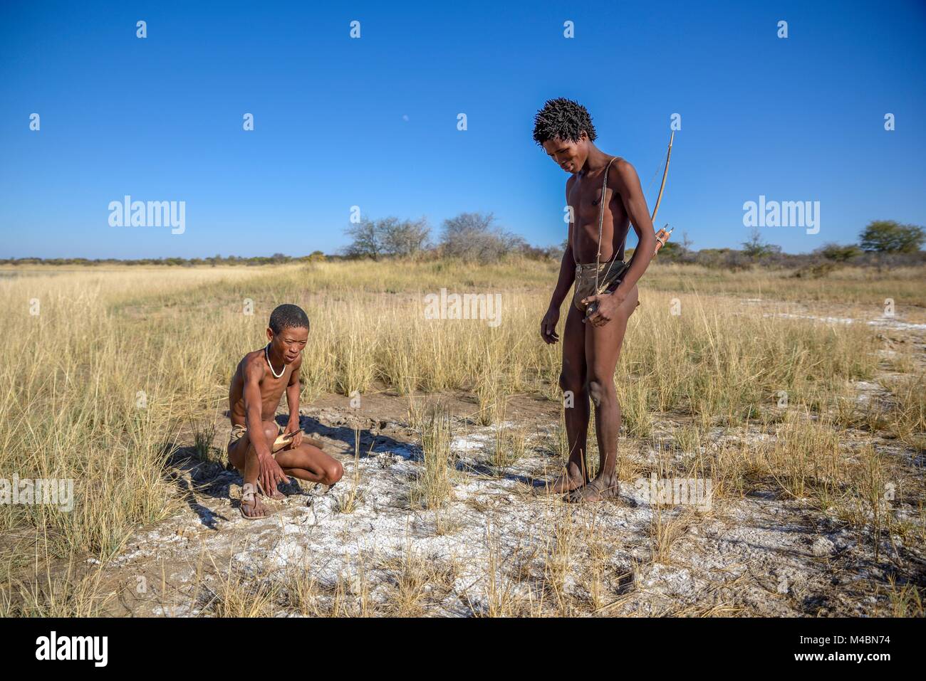 Bushmen of the Ju/' Hoansi-San on traditional hunting with bow and arrow,reading tracks,village //Xa/oba,near Tsumkwe Stock Photo
