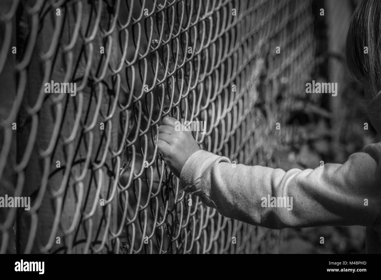 Little girl hand holding fence Stock Photo