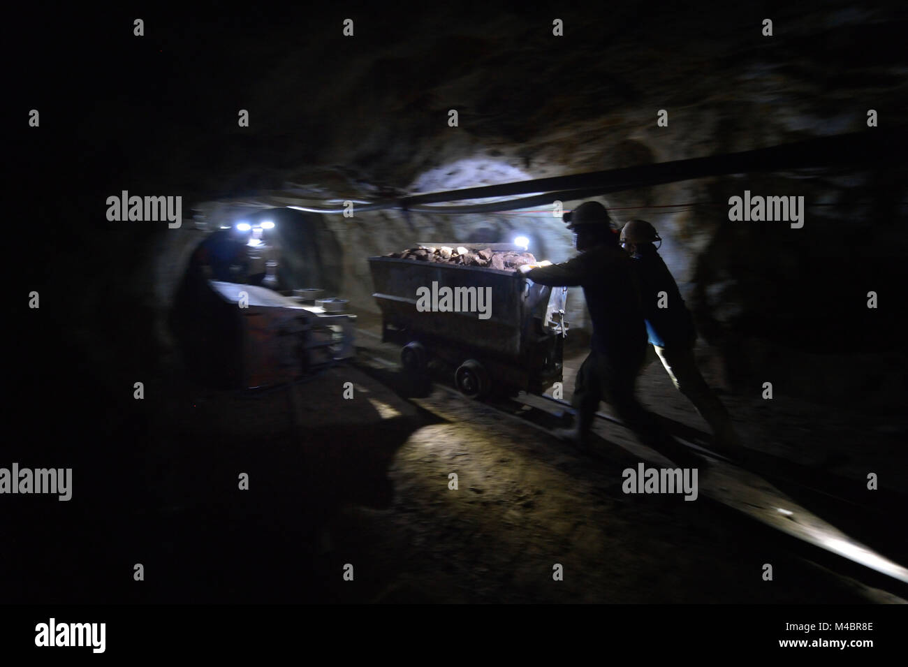 Miners move an ore cart inside a mine in Potosi, Bolivia. The mine produces silver and other metals. Stock Photo
