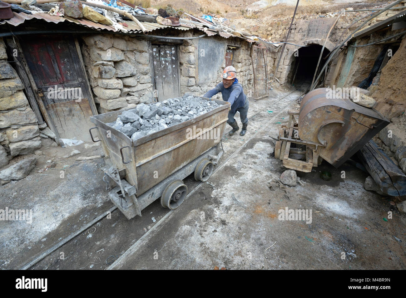 A miner moves an ore cart outside a mine in Potosi, Bolivia. The mine produces silver and other metals. Stock Photo