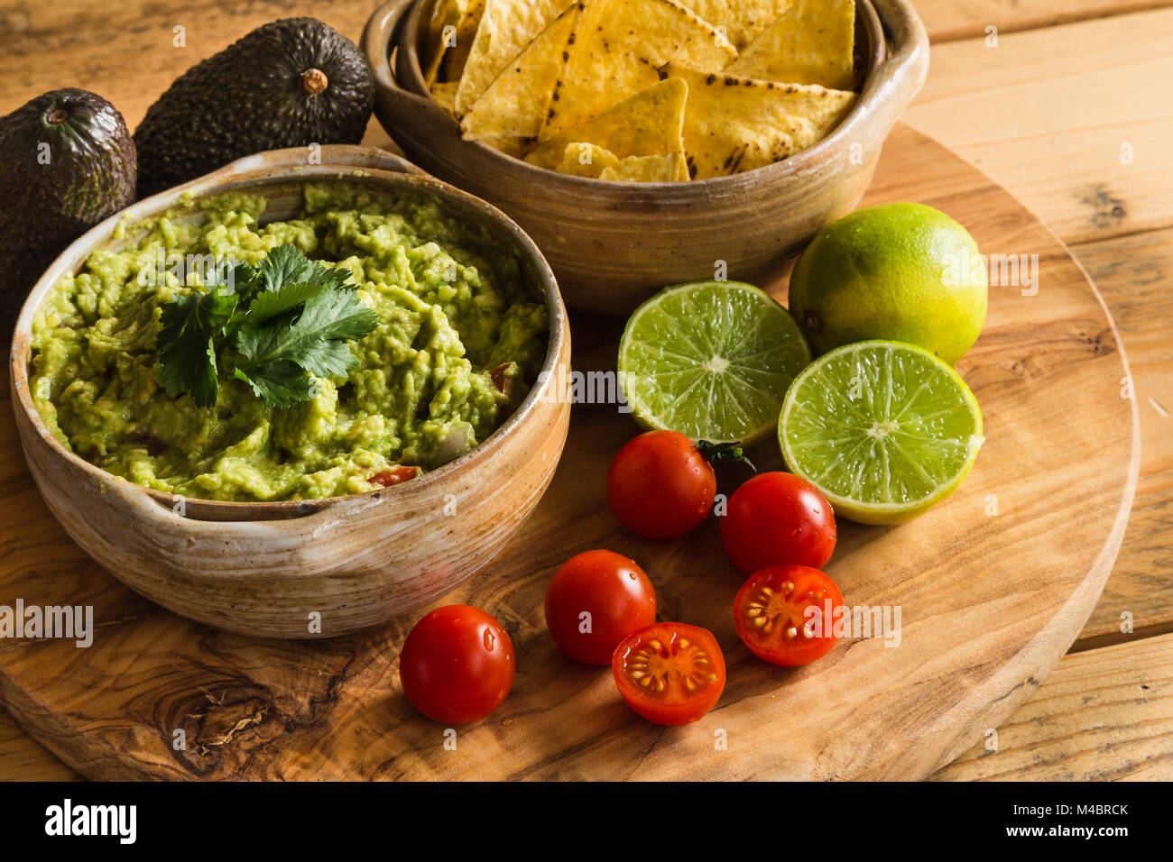 Guacamole dip in bowl with tortilla chips and ingredients Stock Photo