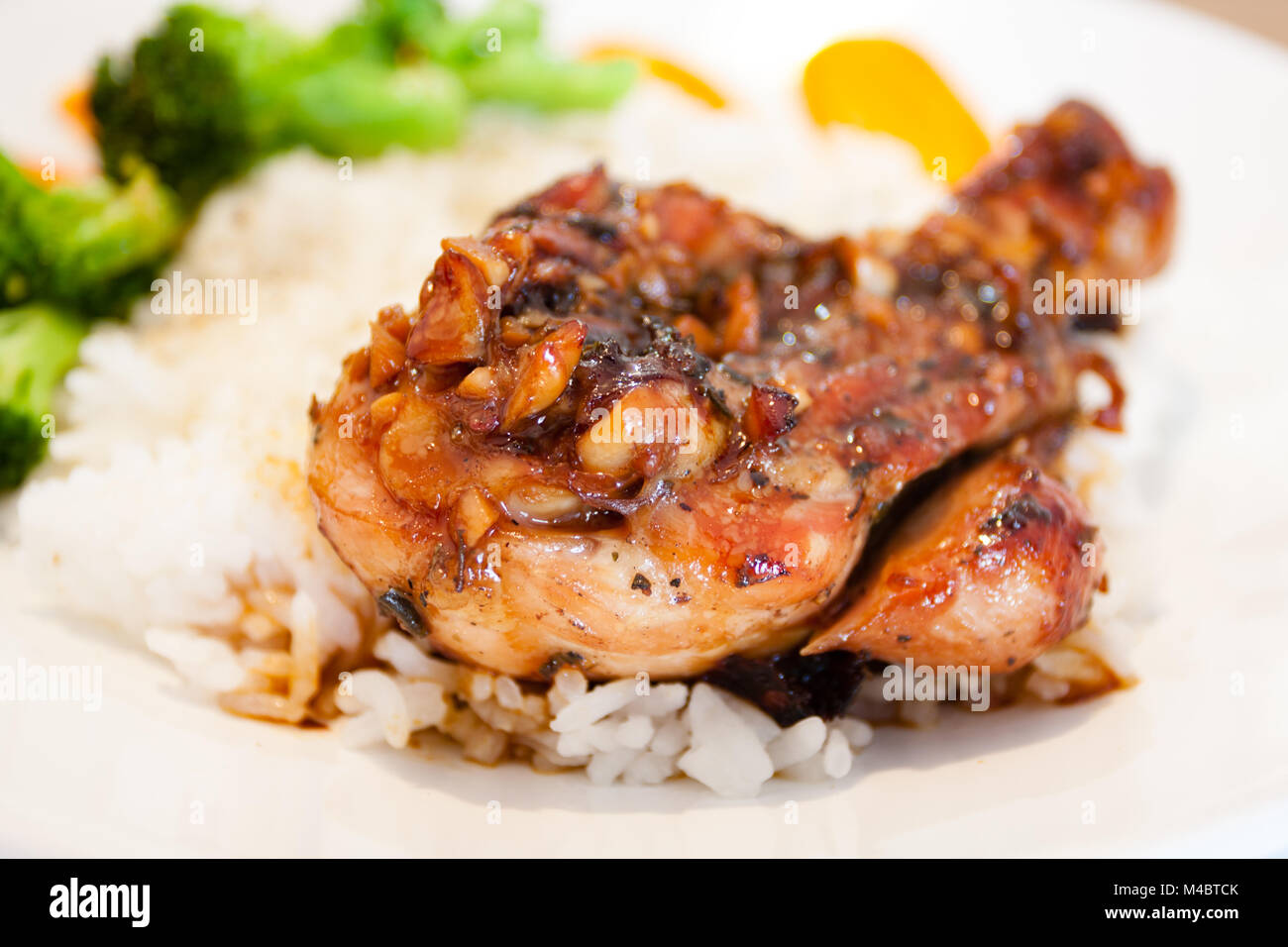 Authentic food prep, juicy roasted chicken drumsticks, homemade, with soy sauce, rice wine, sugar, garlic, oregano; rice with carrot and broccoli Stock Photo