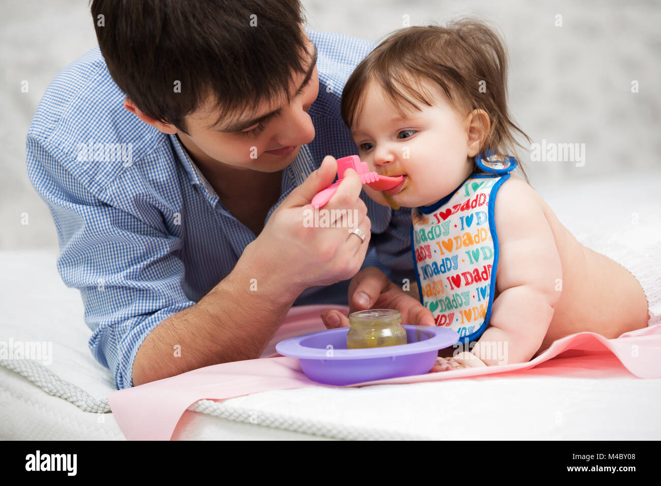 Father feeding baby girl on blanket at home Stock Photo Alamy