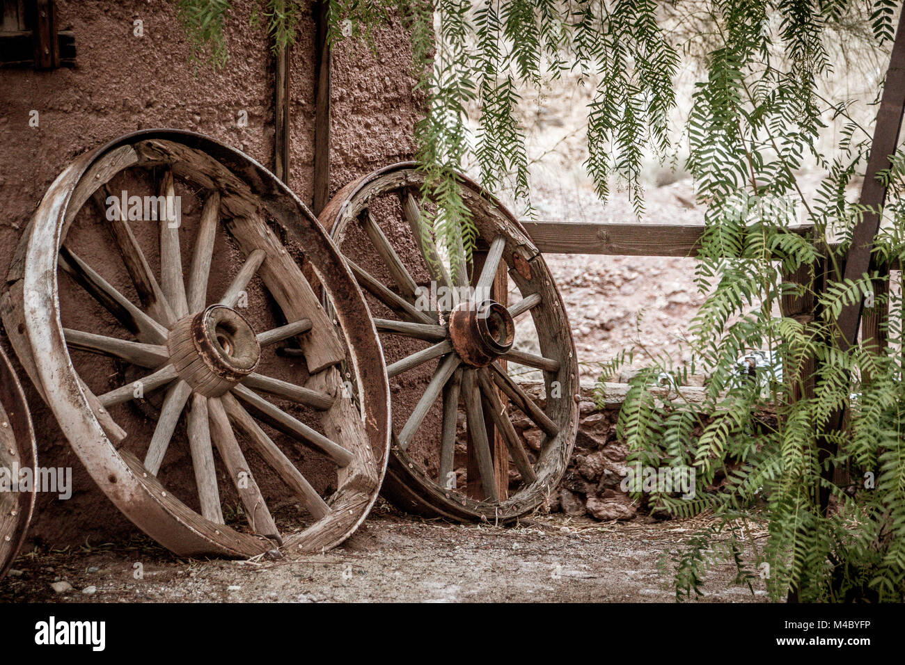 Old broken waggon wheels leaning against a wall Stock Photo