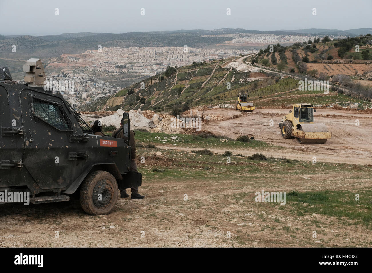 Nativ Ha'avot, Israel. 15th Feb, 2018. Israeli soldiers stand guard as road rollers level the ground near the illegal Jewish outpost of Nativ Ha'avot on 15 February 2018. The Israeli government attempts to postpone the removal of some of the houses in the outpost despite the Supreme Court ruling after accepting the petition of a group of Palestinians who argued the homes had been partially built illegally on their land. Credit: Eddie Gerald/Alamy Live News Stock Photo