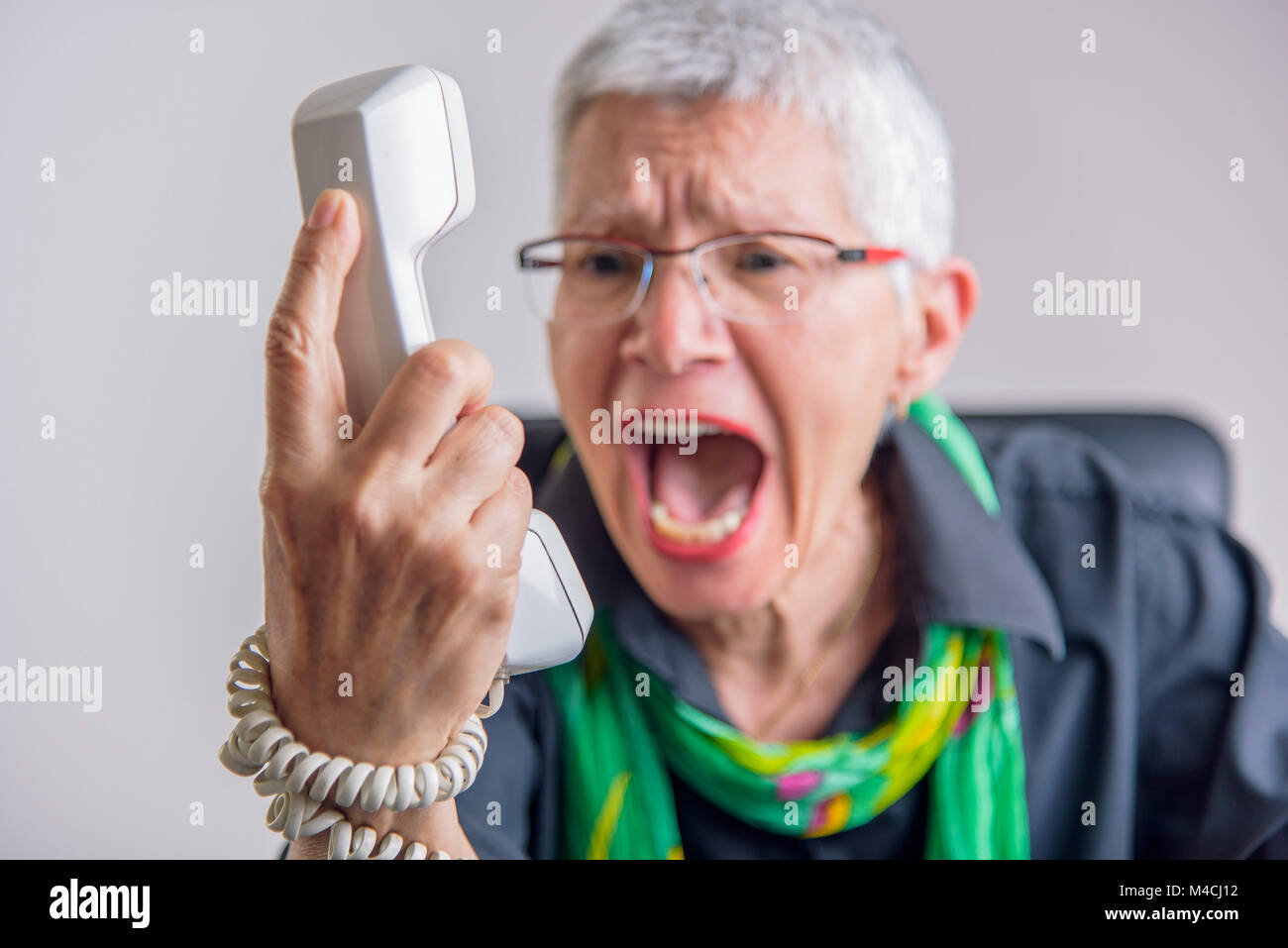 Terrible service, angry senior woman yelling at phone Stock Photo