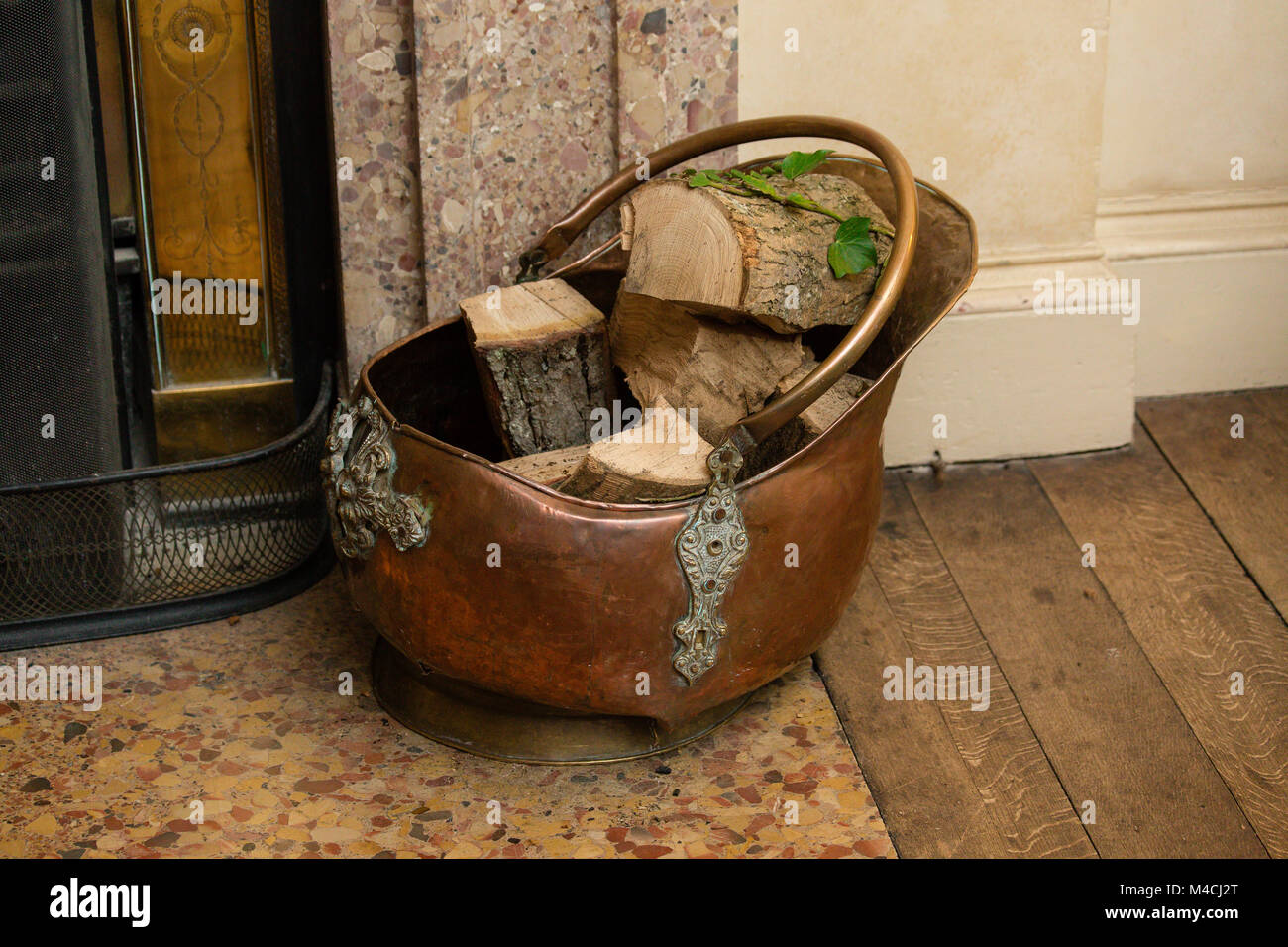 Vintage hammered copper scuttle bucket with logs for domestic fire