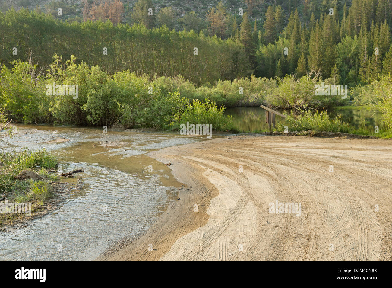 a dirt road with water flowing across it Stock Photo