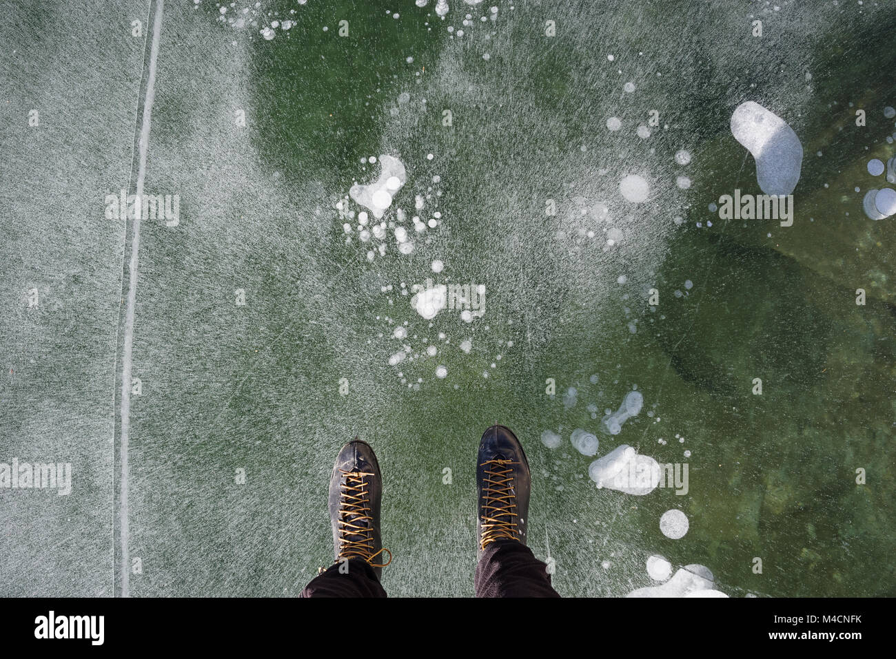 view down while ice skating on a lake showing the end of a man's legs and ice skates Stock Photo