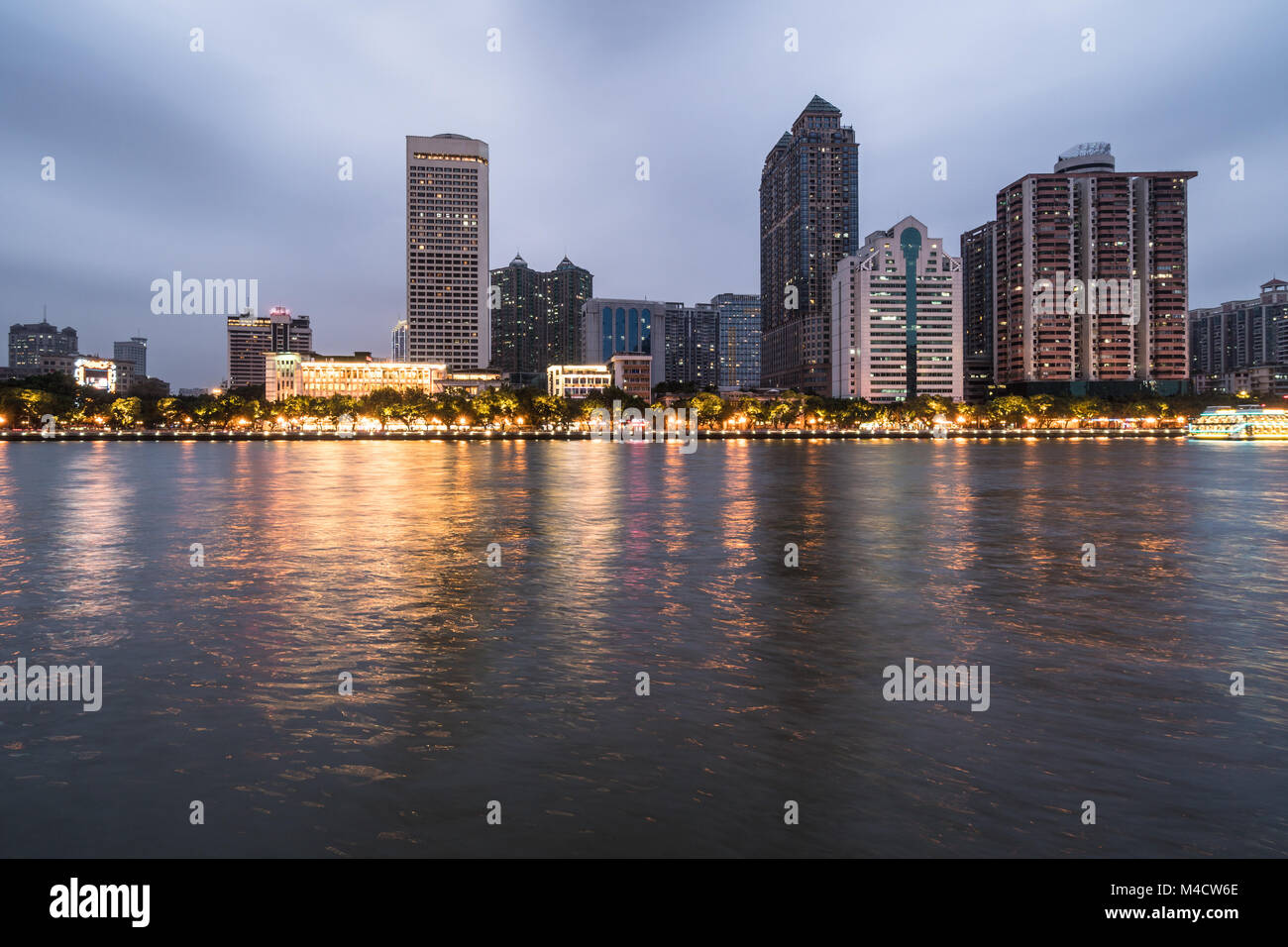Office buildings and hotel tower reflect in the water of the Pearl river that crosses the Guangzhou downtown district in Guangdong province in China a Stock Photo