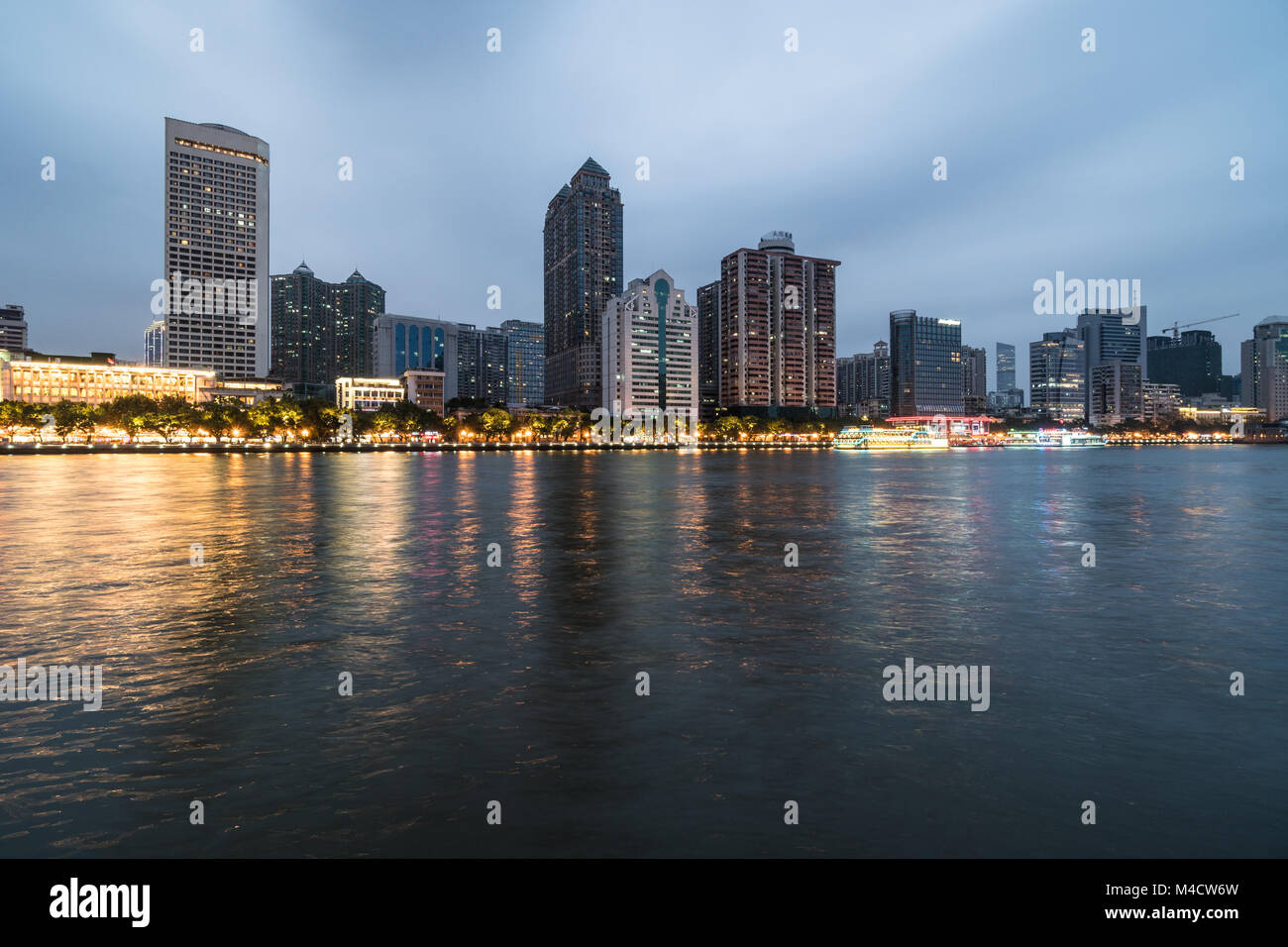 Office buildings and hotel tower reflect in the water of the Pearl river that crosses the Guangzhou downtown district in Guangdong province in China a Stock Photo