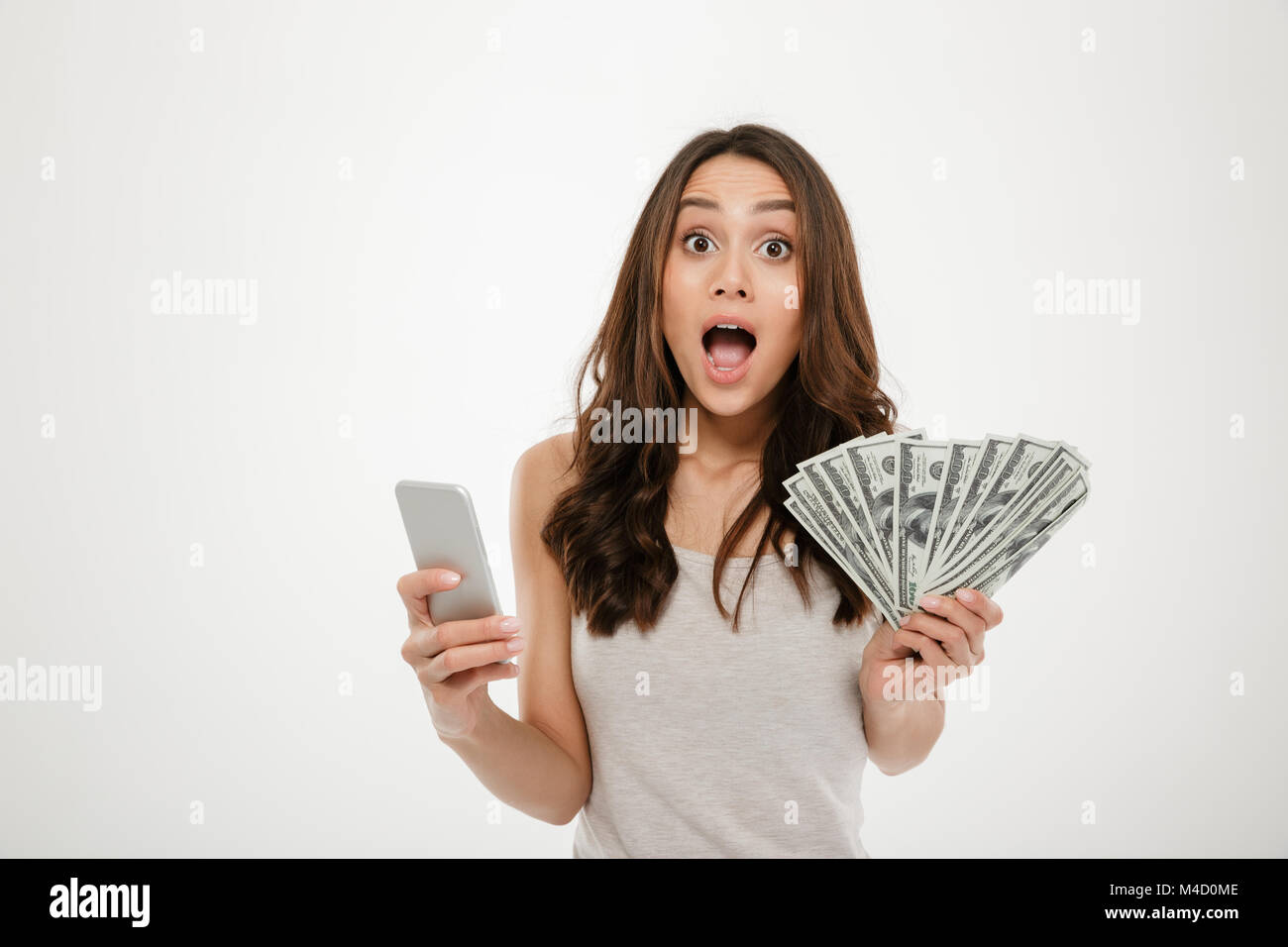 Portrait of attractive brunette female 30s winning lots of money dollar ...