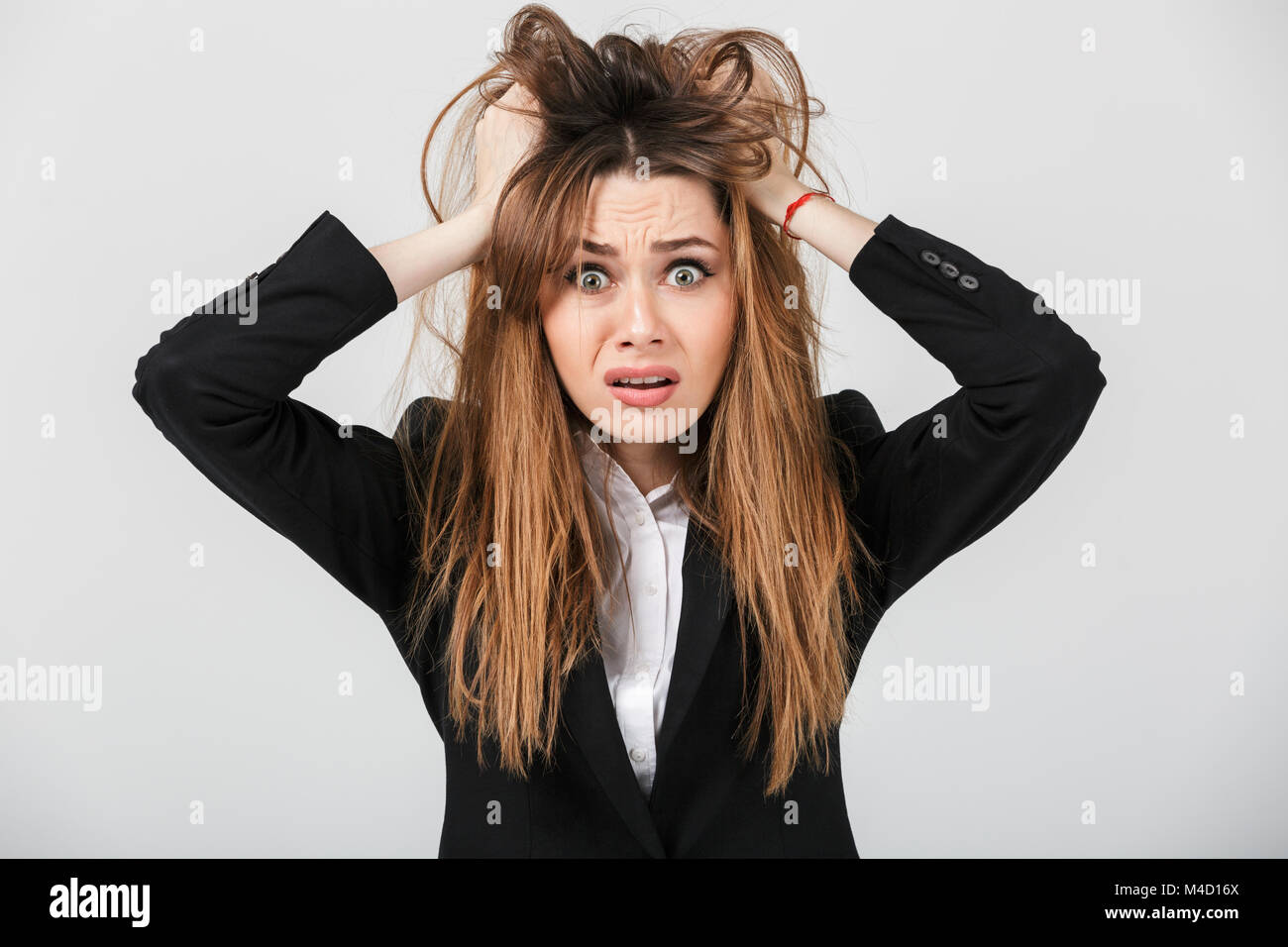 Portrait of a puzzled businesswoman dressed in suit pulling her hair