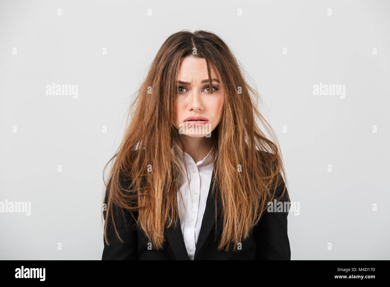 Portrait of an exhausted businesswoman dressed in suit with messy hair  looking at camera isolated over gray background Stock Photo - Alamy