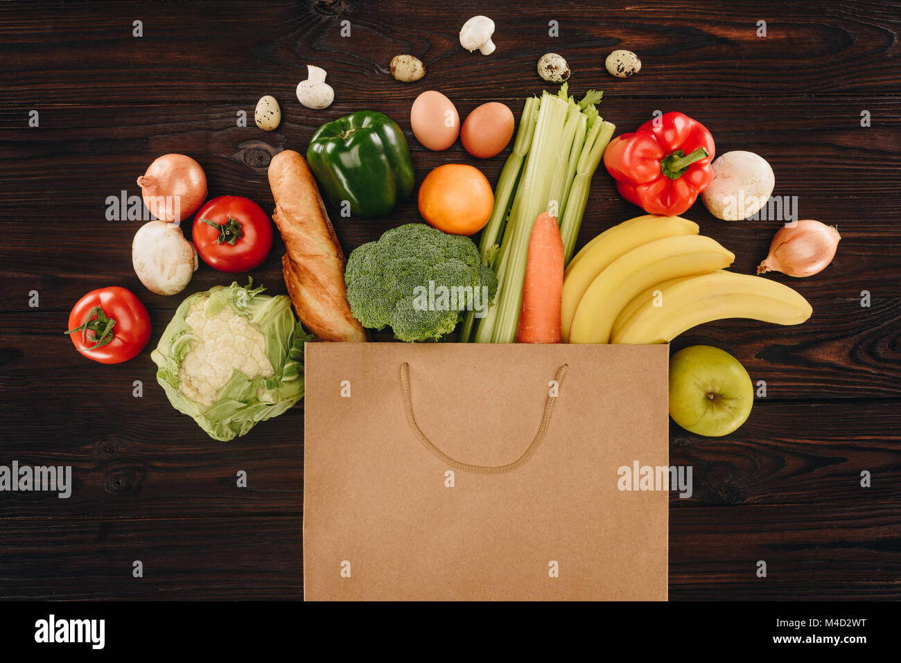 top view of different vegetables and fruits in paper bag on wooden ...
