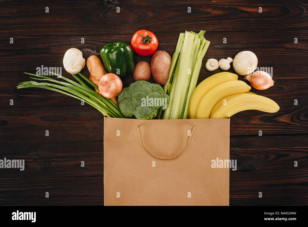 top view of different vegetables and fruits in shopping bag on wooden ...