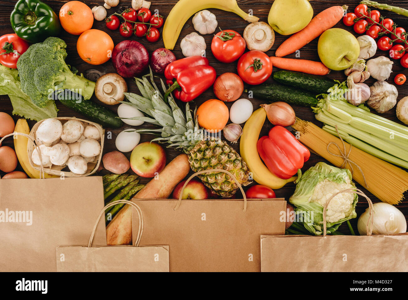 top view of paper bags covering vegetables and fruits on wooden table ...