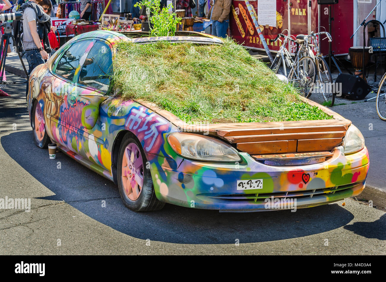 Car down Kensington Market covered in Grafitti and plants Stock Photo