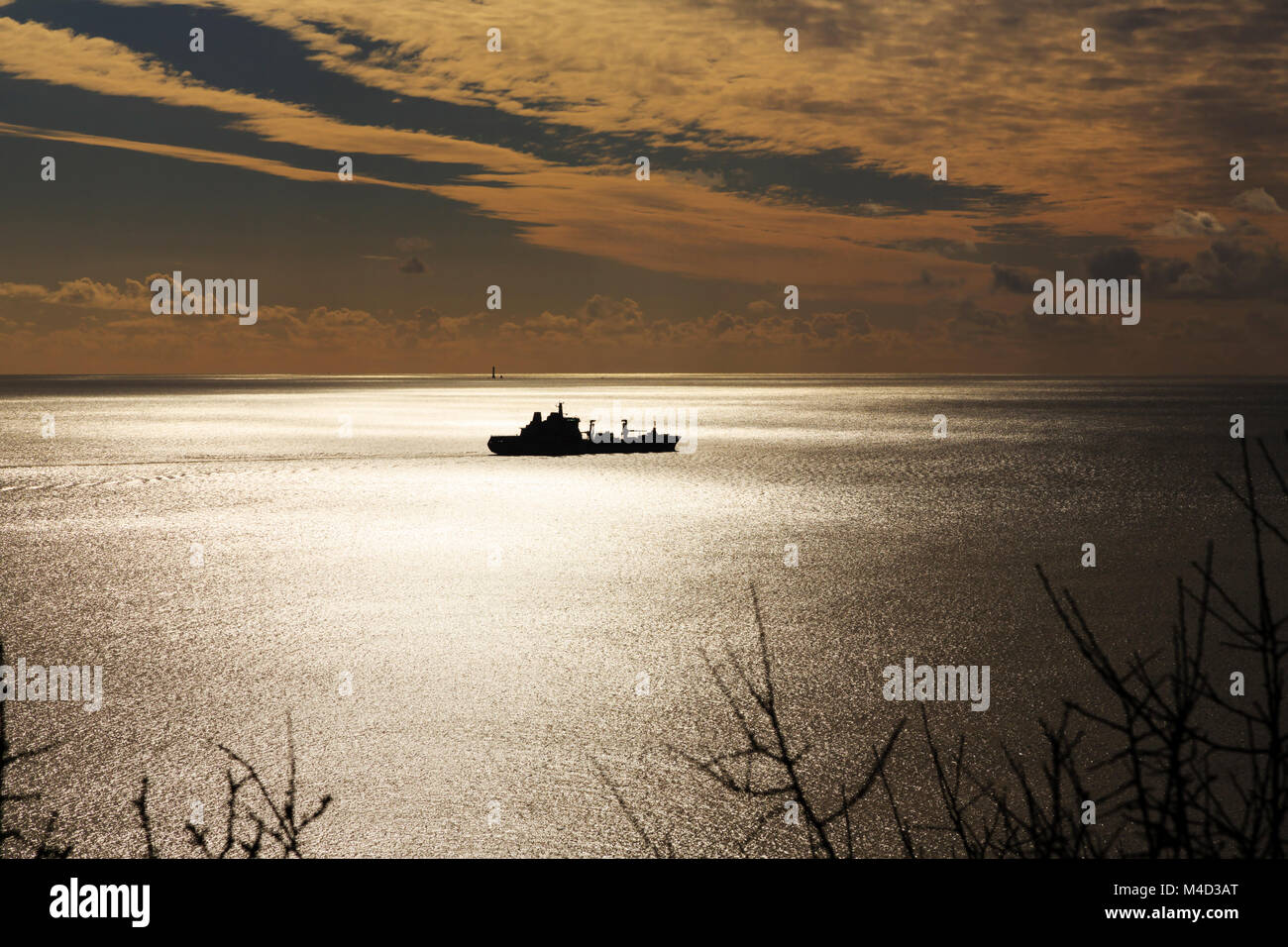 Royal Fleet Auxiliary RFA Tidespring, A136,  replenishment tanker silhouetted in Plymouth Sound with the setting sun and Eddystone lighthouse behind i Stock Photo