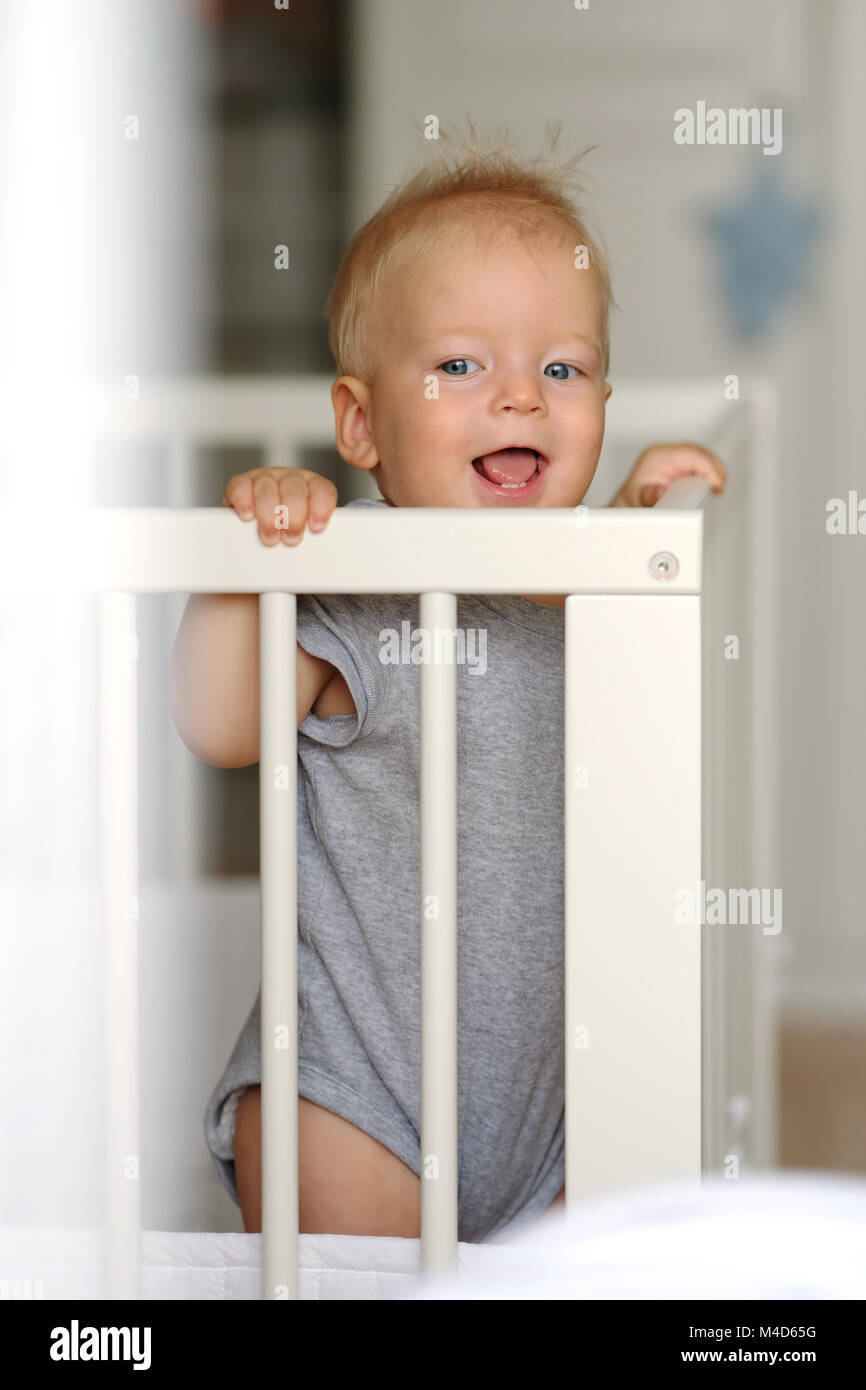 Baby boy standing in crib Stock Photo Alamy